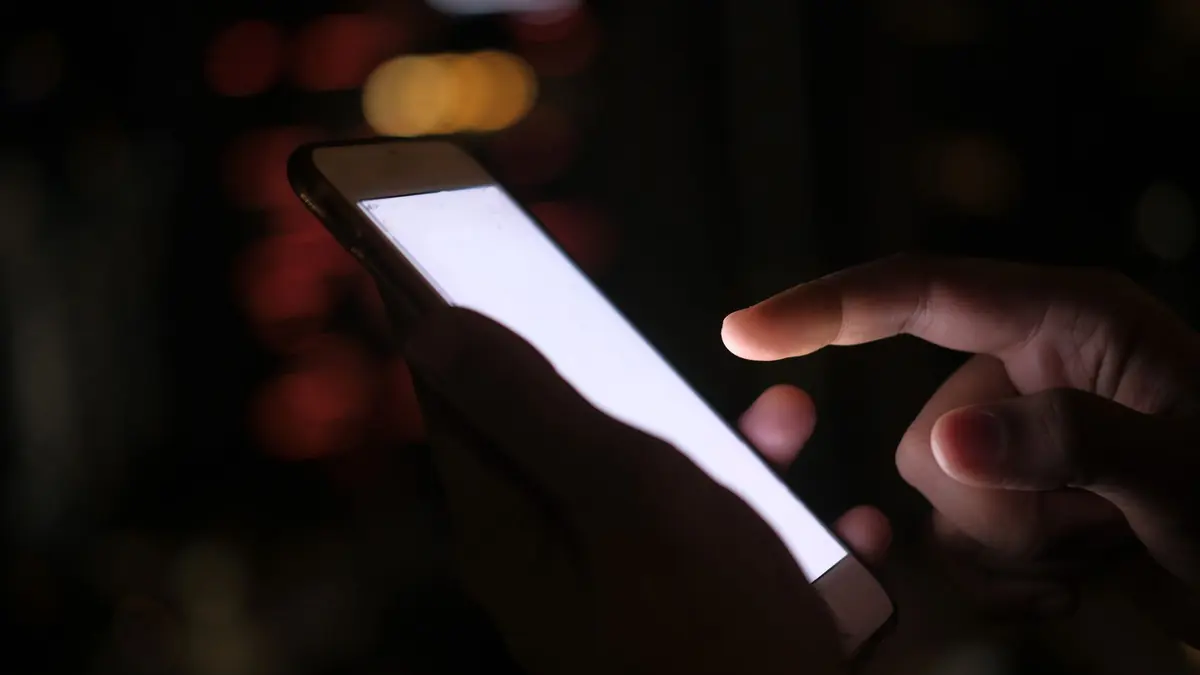 Smartphone allumé dans le noir pour consulter un avis iptv adulte en toute discrétion
