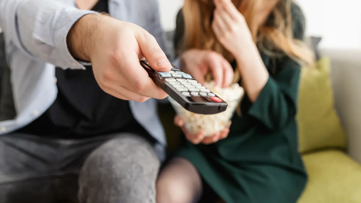 Couple avec télécommande et pop-corn devant un iptv adulte TiviMate en 4K